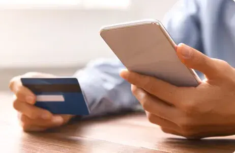 Person holding phone and credit card Person holding phone and credit card